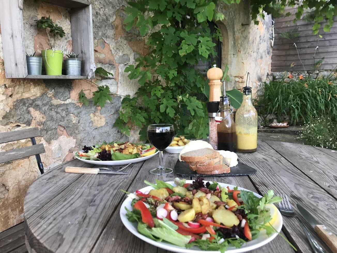 Ein Holztisch mit angeordneten Speisen, einem Glas Rotwein und Flaschen Olivenöl.