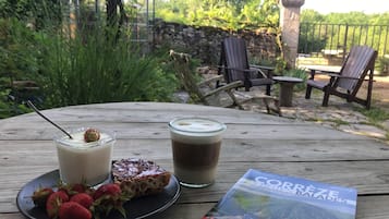 Een houten tafel met een glas melk, een plakje brood met aardbei, een glas koffie en een reisgids.