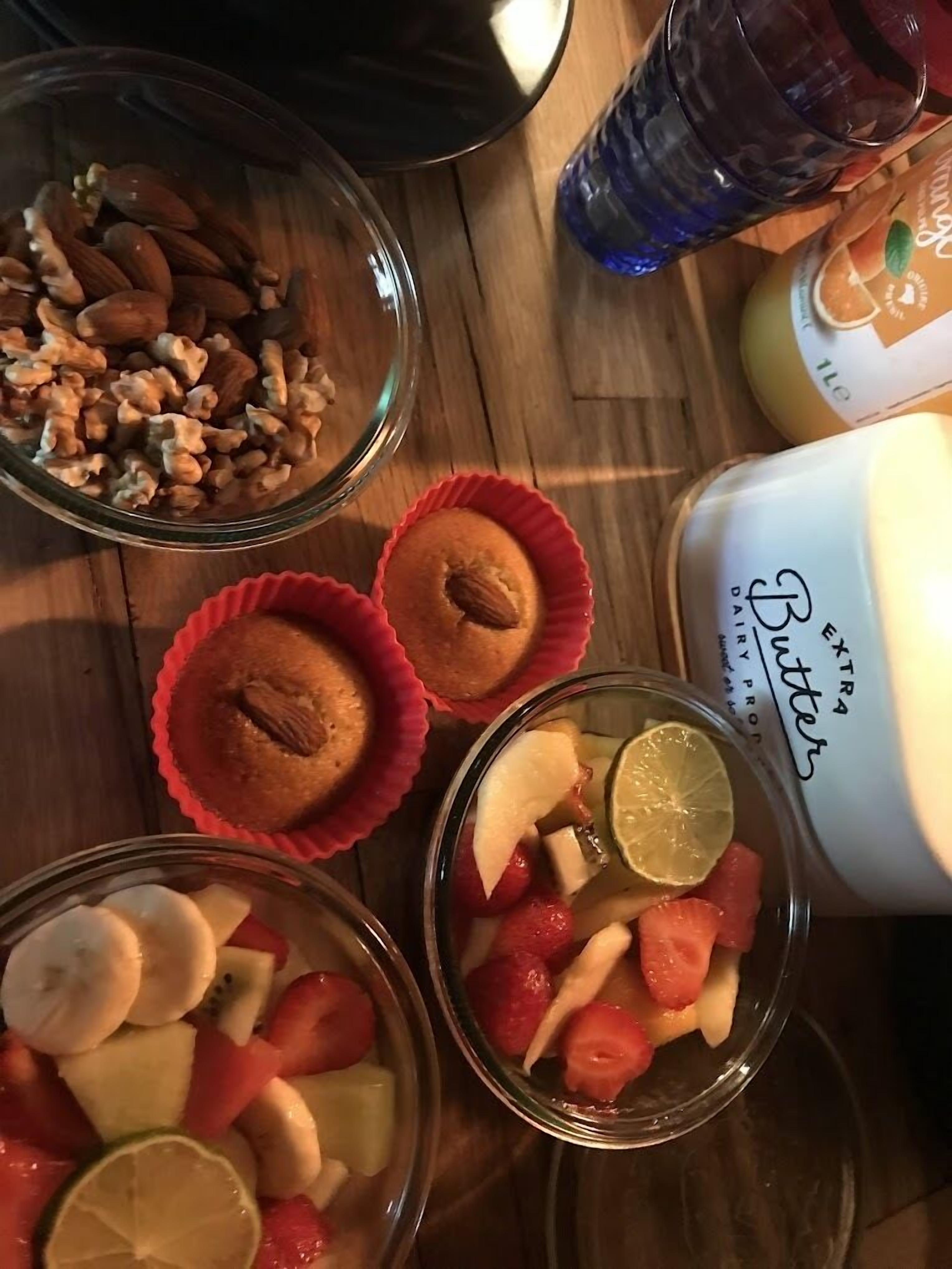 Ett träbord med olika sorters mat, inklusive muffins, nötter och frukt.