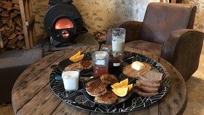 Un rincón comedor acogedor con una mesa dispuesta para el desayuno, que incluye panqueques, tostadas y bebidas.