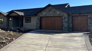 A two-story house with a stone facade, a large garage, and a concrete driveway.