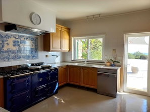 Enjoy cooking in this well-lit kitchen with a central island, stove, and oven, plus a large window offering a view of the outdoors.