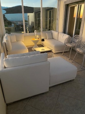 Relax in this outdoor living space with a comfortable sofa and armchairs, perfect for taking in the views of the surrounding landscape.