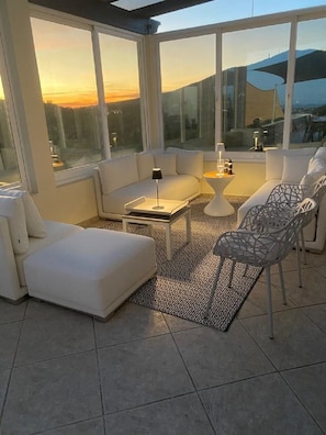 Relax in a stylish outdoor space with a sectional sofa, chaise lounge, and metal chair, surrounded by expansive views of the surrounding landscape.