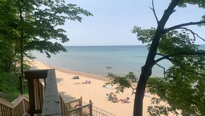A beach with a wooden deck and a railing, overlooking a sandy shore with people relaxing. - Whittier Cottage (Douglas)