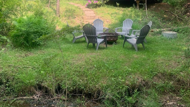 A house with a deck, surrounded by lush greenery and a small stream. - Whittier Cottage (Douglas)