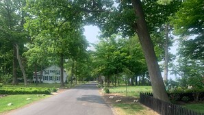 A tree-lined street with a white house on the left. - Whittier Cottage (Douglas)