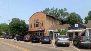 A street view with parked cars, a pet boutique, and a building with a curved facade. - Whittier Cottage (Douglas)