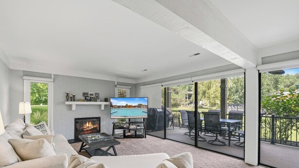 A living room with a fireplace, a television, and a balcony with outdoor furniture.