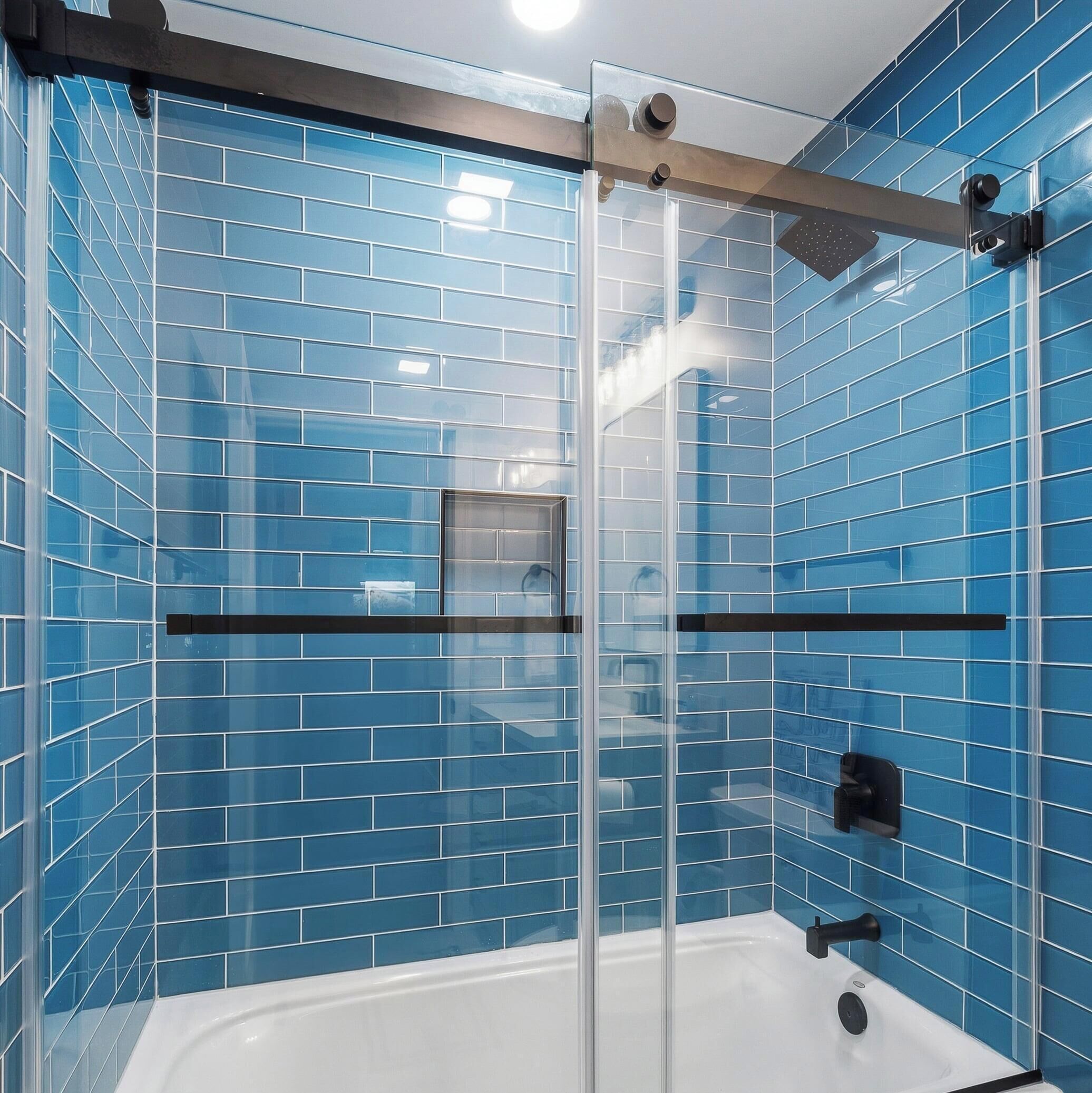 Une douche en verre avec des murs recouverts de carreaux bleus et une baignoire blanche.