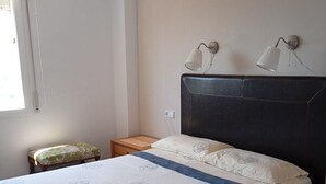 Een slaapkamer met een groot bed, twee nachtkastjes, een raam met gordijnen en twee wandlampen.