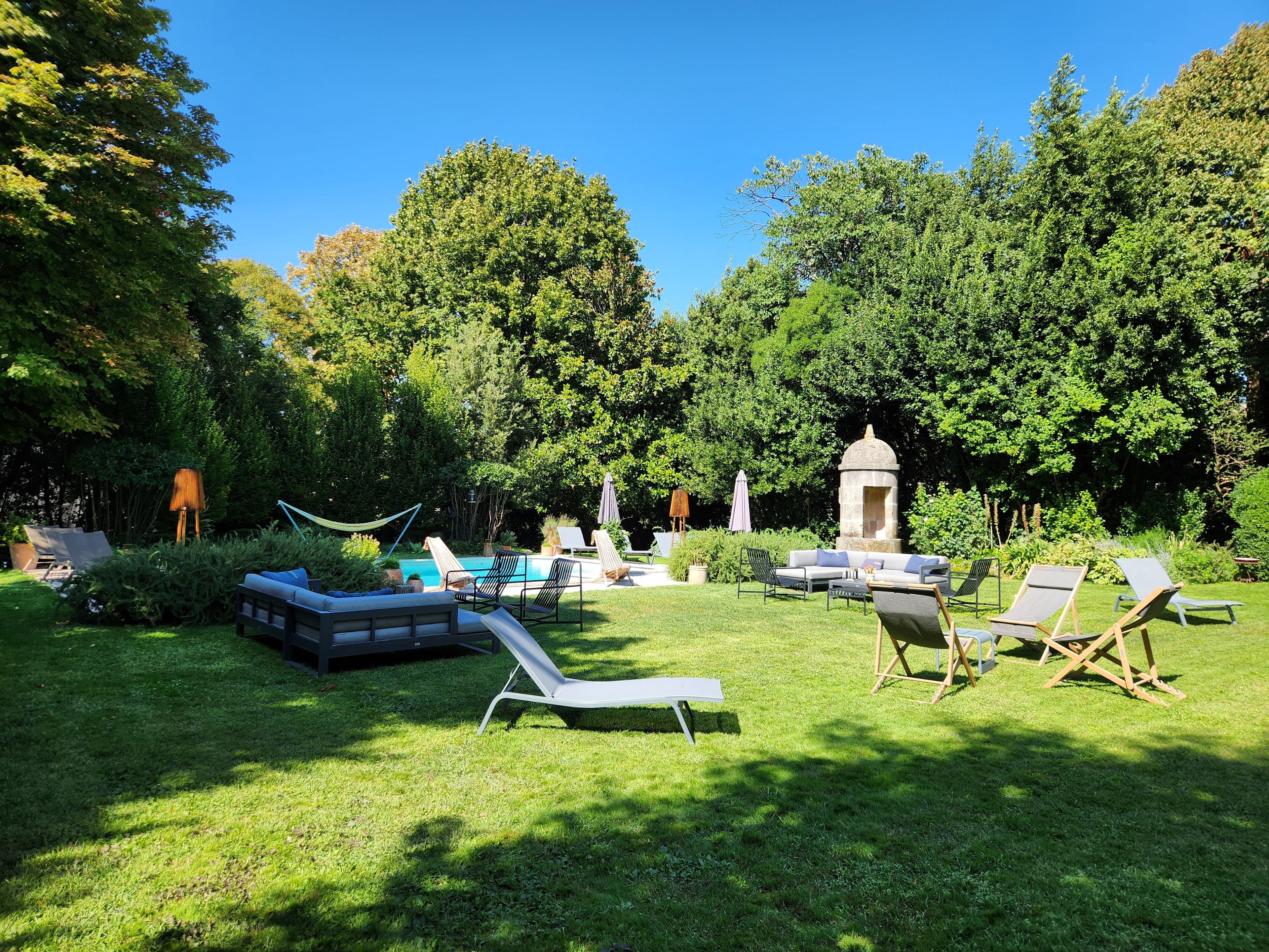 Un jardin bien entretenu, doté d’une piscine, de chaises longues et d’un belvédère.