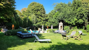 Un jardin bien entretenu, doté d’une piscine, de chaises longues et d’un belvédère.