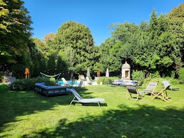Um jardim bem cuidado com piscina, espreguiçadeiras e um gazebo.