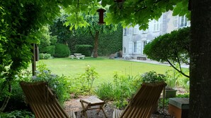 A garden with two wooden chairs, a small table, and a hanging light fixture. - Logis des Tourelles (Cognac)