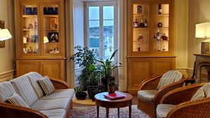 A cozy living room with wicker furniture, a fireplace, and wooden cabinets displaying bottles. - Logis des Tourelles (Cognac)