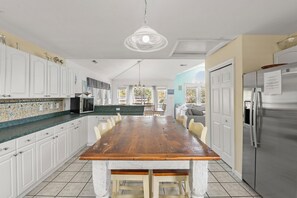 A spacious kitchen with a wooden dining table, white cabinets, and a stainless steel refrigerator.
