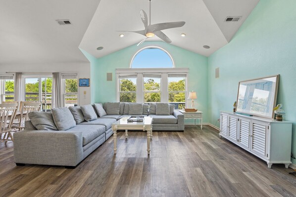 A spacious living room with a large sectional sofa, a coffee table, and a ceiling fan.