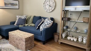 A living room with a blue sofa, a clock, a television, and a glass cabinet with decorative items. - Cozy apartment getaway in Holland (Holland)