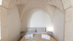 A room with a bed, two pillows, a nightstand, and a towel on the bed. - CA'milla Suite Home (Ostuni)