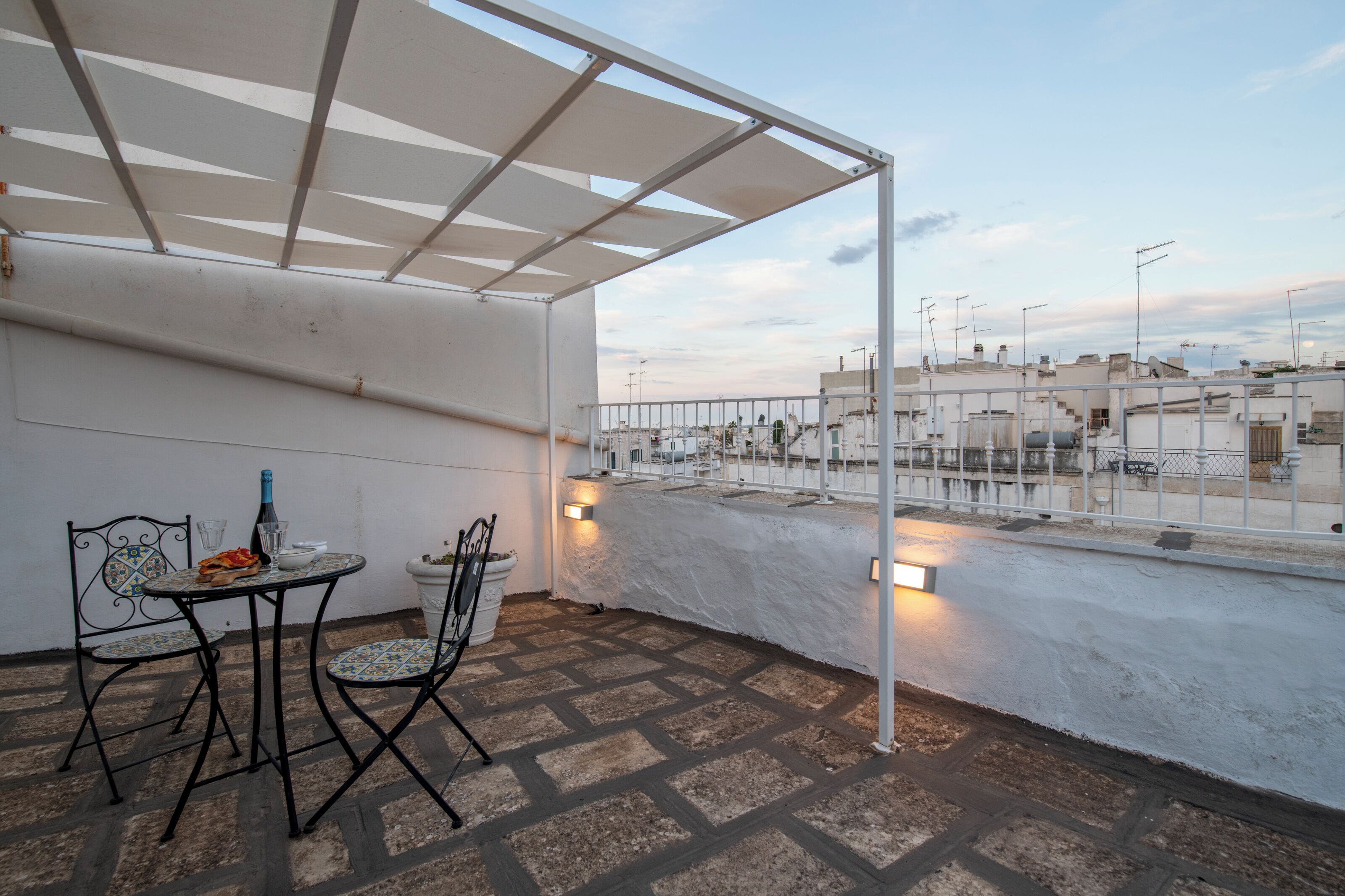 Una terraza en la azotea con mesa y sillas, una pérgola y vistas de la ciudad.