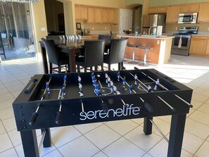 Uma mesa de futebol de mesa em uma cozinha moderna com armários de madeira e uma área de refeições.