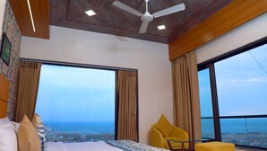 A hotel room with a large bed, a yellow armchair, and a view of the sea. - Hotel The Grand Ladhukara (Dwarka)