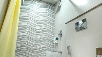 Une salle de bain avec des toilettes blanches, un rideau de douche et un sol carrelé.