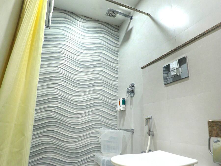 Une salle de bain avec des toilettes blanches, un rideau de douche et un sol carrelé.