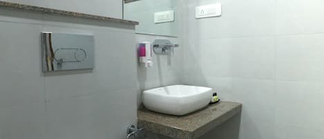 A bathroom with a toilet, sink, mirror, and a small window.