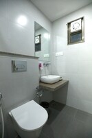 A bathroom with a toilet, sink, mirror, and a small window.