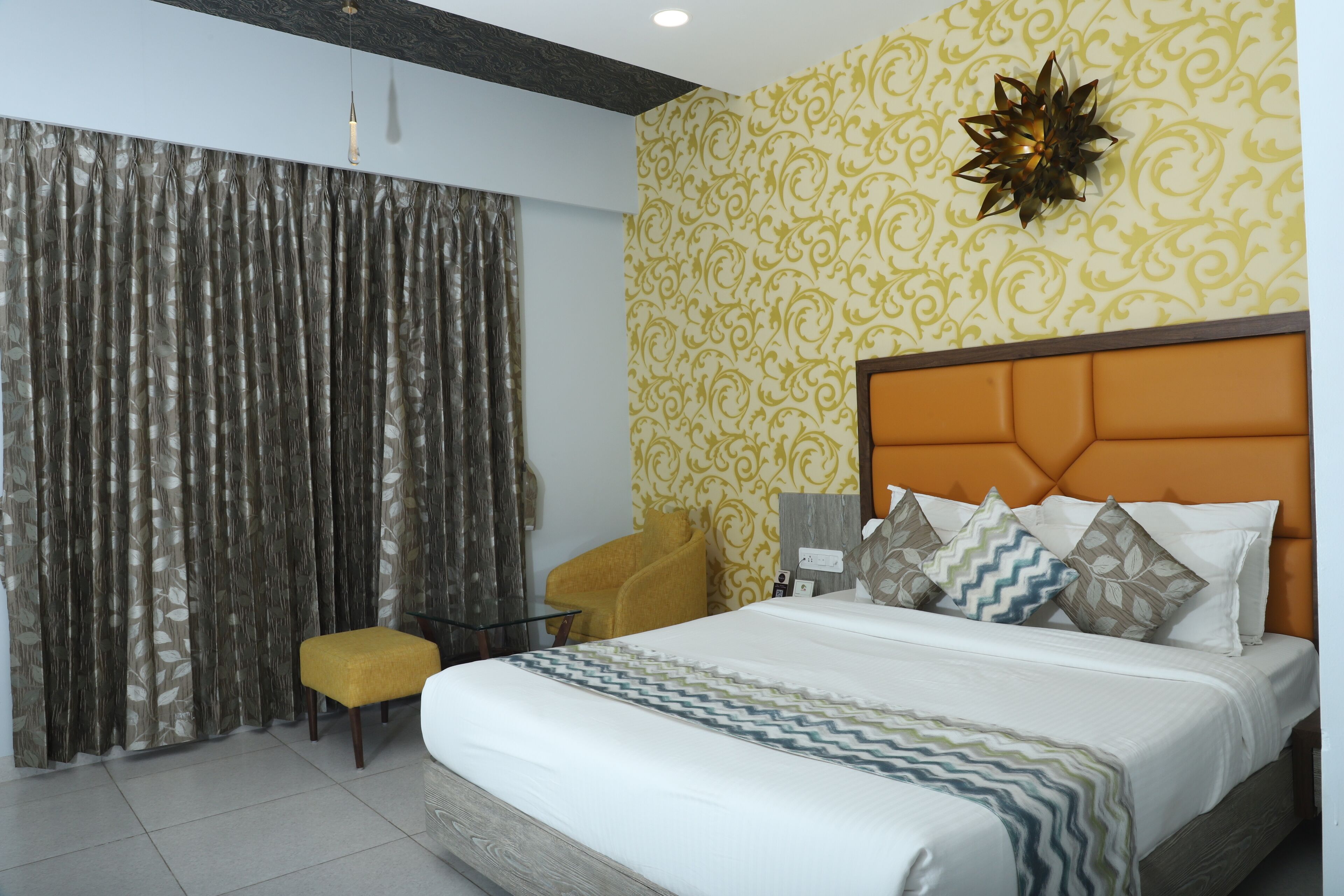 Une chambre d’hôtel avec un lit, une petite table, une chaise et un rideau.