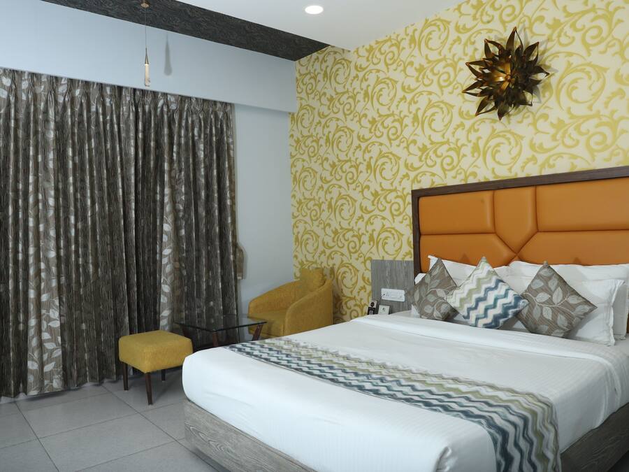 Une chambre d’hôtel avec un lit, une petite table, une chaise et un rideau.
