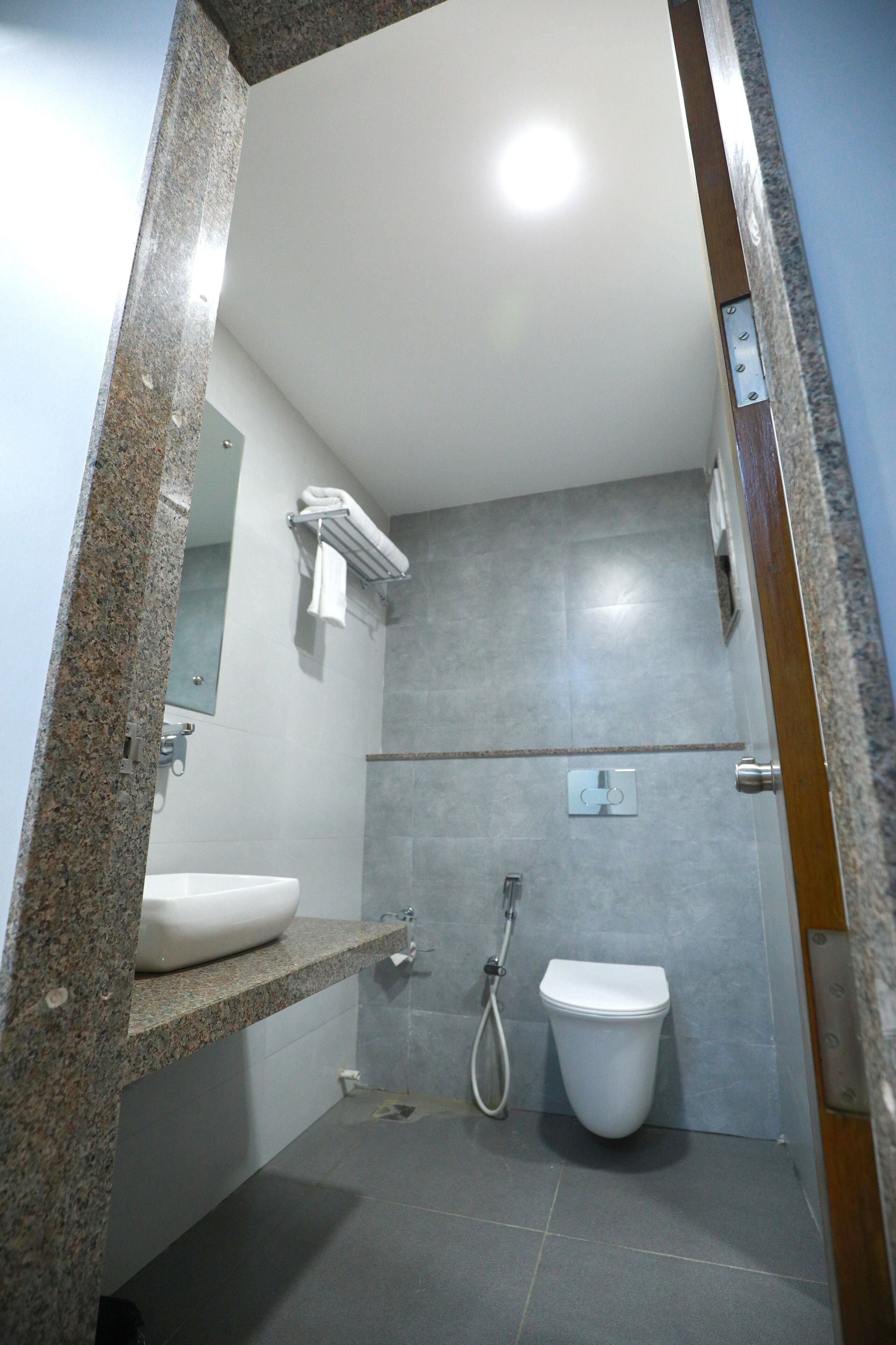A bathroom with a granite countertop, a white sink, a toilet, and a shower.