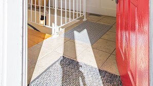 Ein Zimmer mit einer weißen Tür, einer roten Tür, einem weißen Geländer, einer Deckenleuchte und einem gemusterten Teppich.