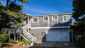 Ein zweistöckiges Haus mit einer Veranda, einer Garage und einer Treppe, die zum zweiten Stock führt.