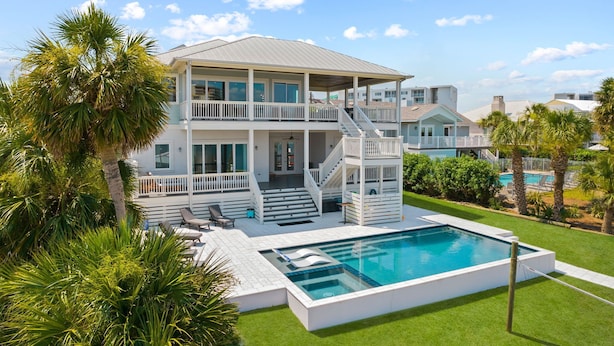 Una casa de dos pisos con piscina, terraza techada y escalera que lleva al nivel superior.