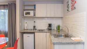 Una cocina compacta con microondas, cafetera y lavabo.