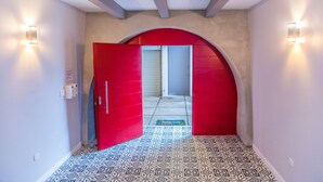 Un pasillo con baldosas de diseño, una puerta roja y una pequeña alfombra.