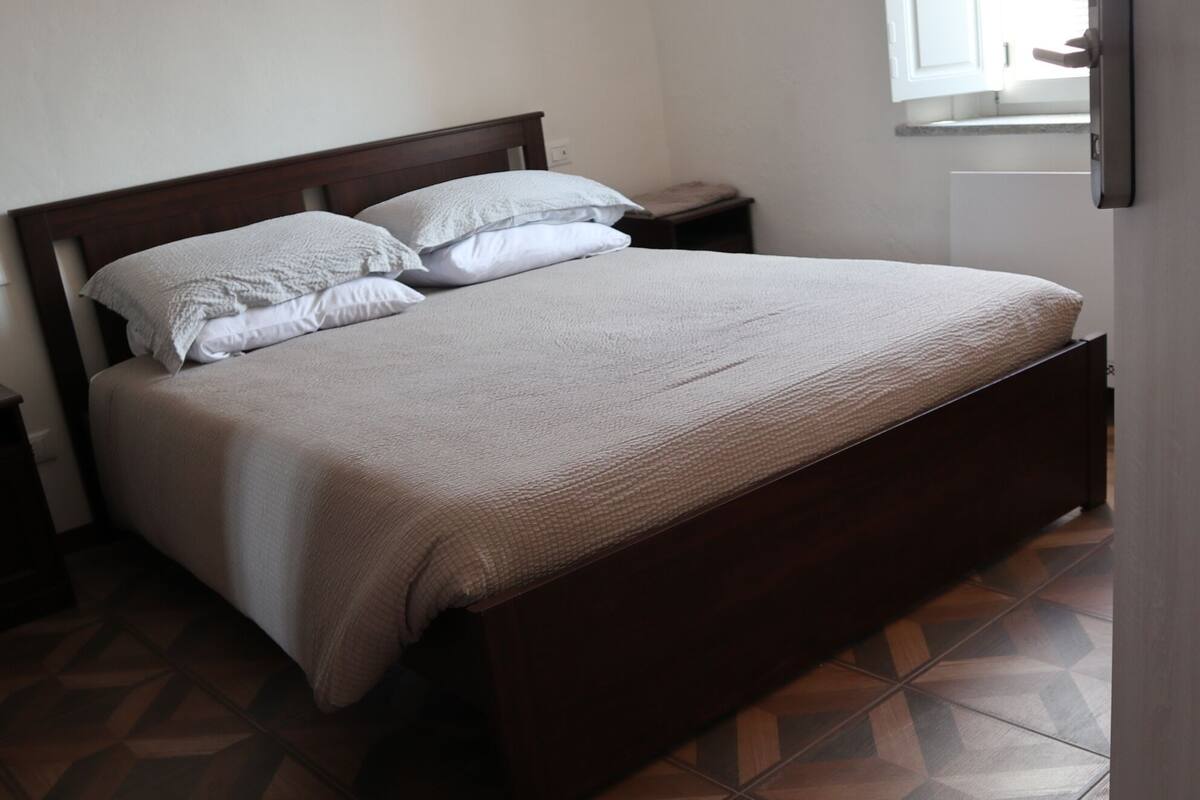 A bedroom with a wooden bed, white bedding, and a geometric patterned floor.
