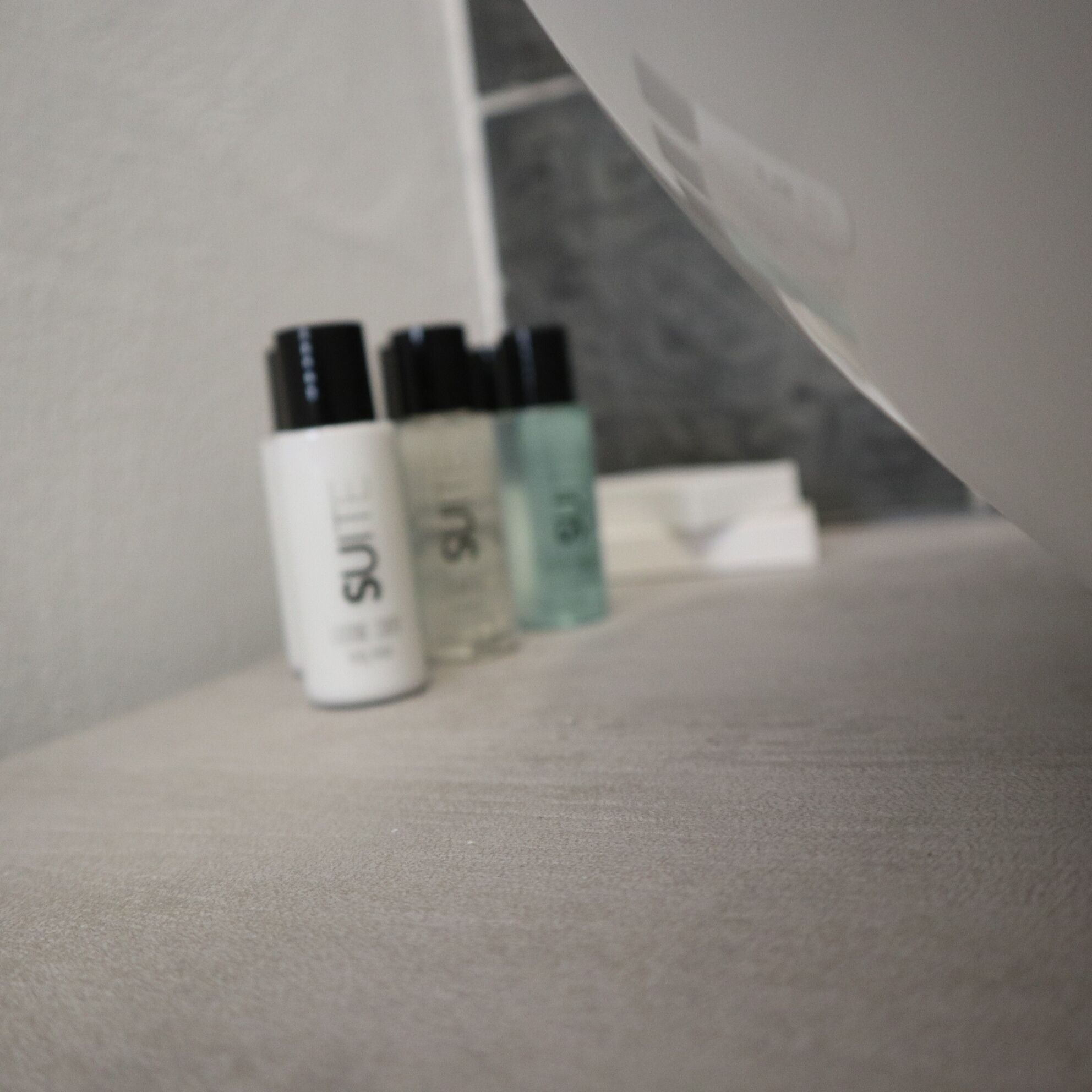 A bathroom with a white sink and three bottles of liquid soap.