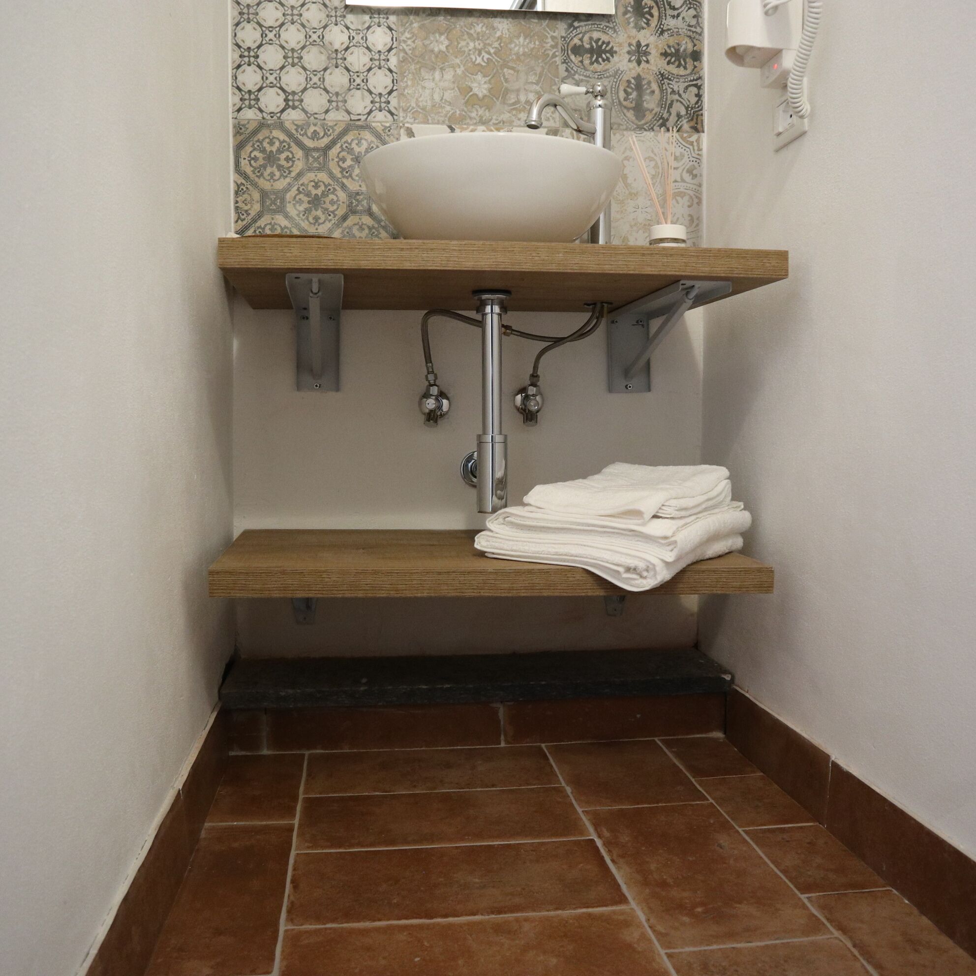 A bathroom with a white sink, a towel rack, and a tiled floor.