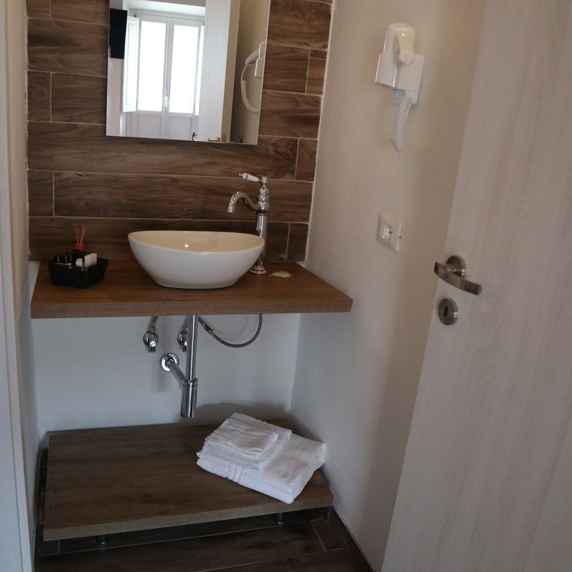 A bathroom with a white sink, a wooden countertop, a mirror, a towel rack, and a telephone.