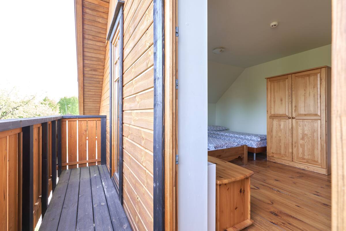 A bedroom with a wooden floor, a bed with a patterned bedspread, and a wardrobe.