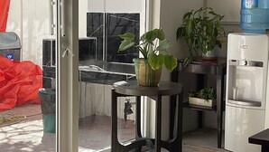 Una cocina con puerta de vidrio corredera que da a un espacio exterior, dispensador de agua y plantas en macetas.