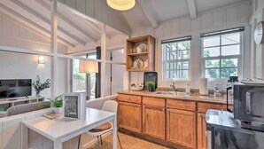 Una cocina moderna con armarios de madera, horno empotrado y comedor con mesa y sillas blancas.