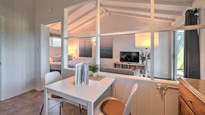 Un interior moderno con zona de comedor, sofá, televisor y ventana con cortinas.