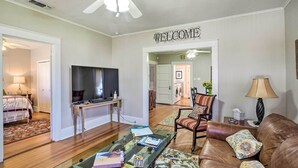 A living room with a TV, a glass coffee table, a brown leather sofa, and a 'WELCOME' sign. - Georgetown Vacation Rental Close to Town Square! (Georgetown)