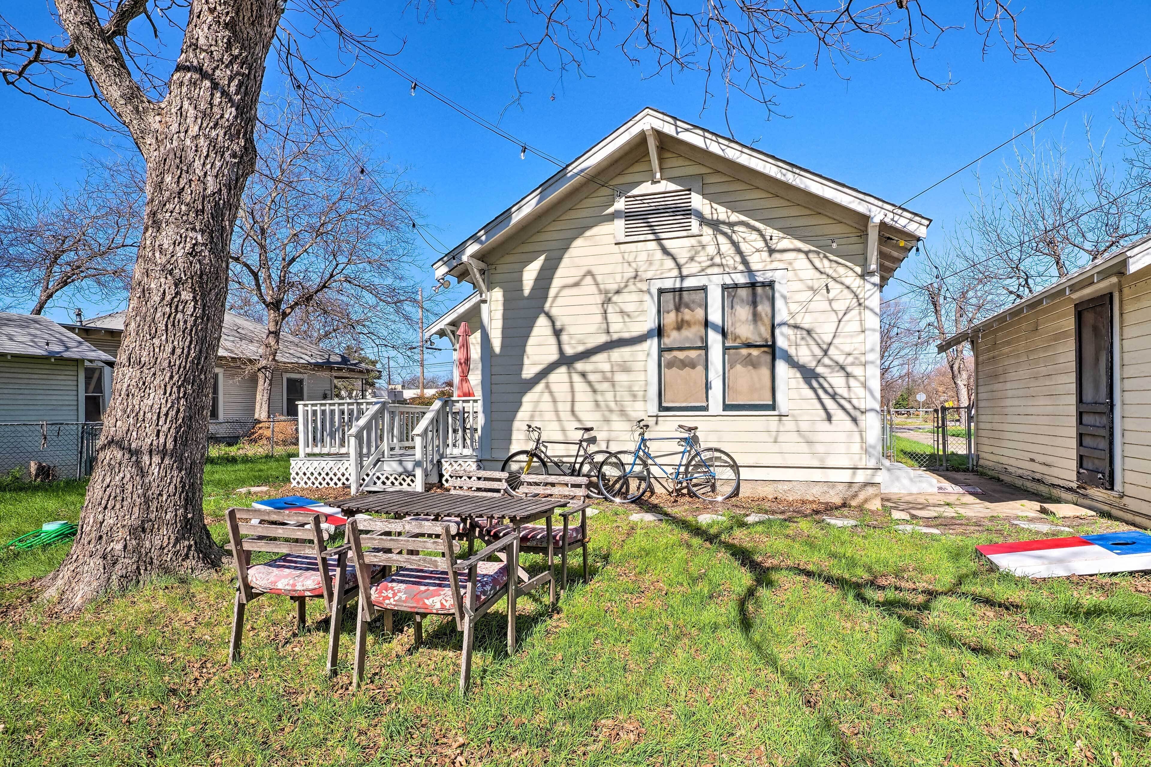 A small house with a porch, a table with chairs, and bicycles parked outside.