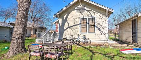 A small house with a porch, a table with chairs, and bicycles parked outside.
